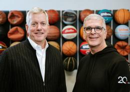 Photo of Charlie Thornton and Marc Farha in front of a wall of basketballs